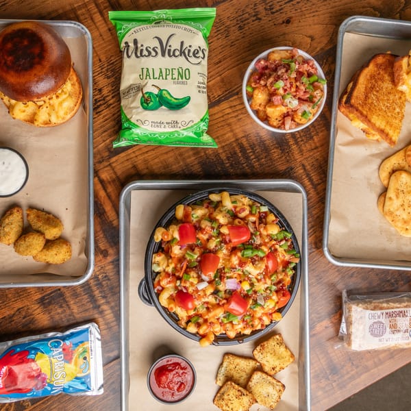 An overhead shot of a Mix & Mac Kitchen spread, featuring mac and cheese, a burger, and sides.